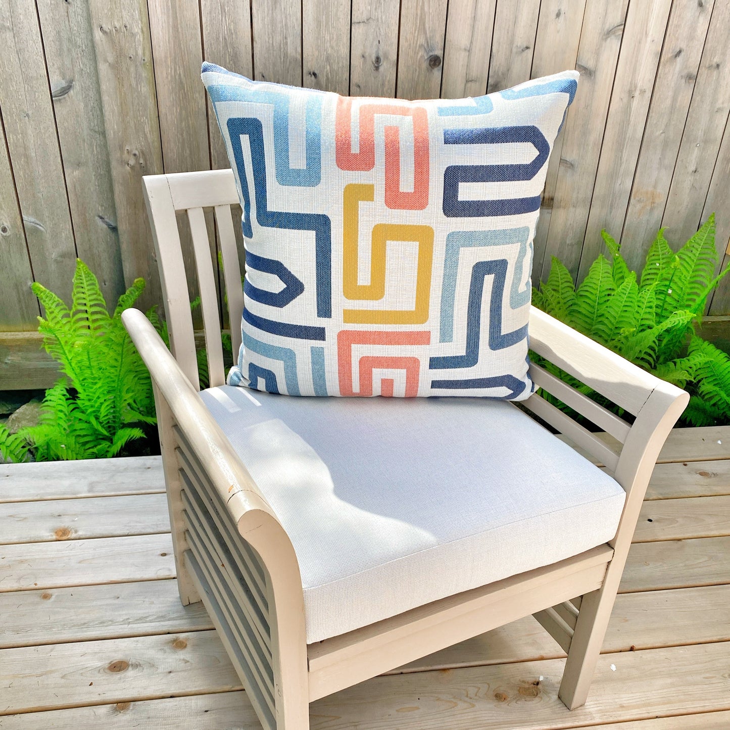 sunbrella pillow in geometric peach, yellow, and navy blue